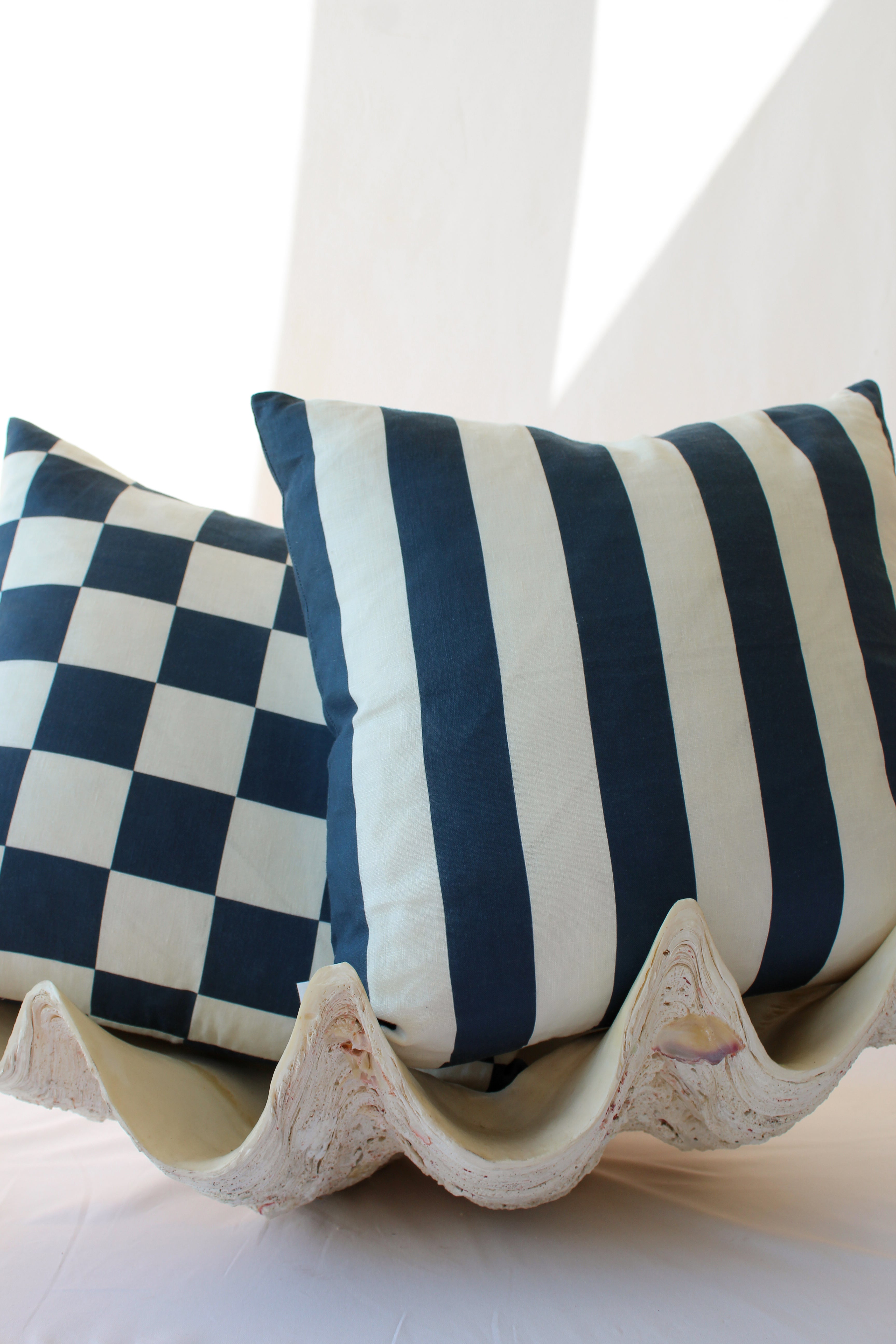 Navy checkered and striped double sided cushions styled in a clam for a coastal aesthetic